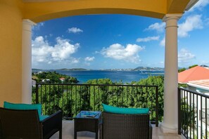 Un balcon doté de meubles en osier et offrant une vue sur la mer.