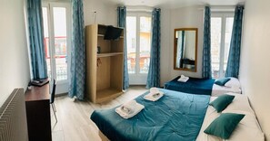 Una habitación de hotel con cama, armario, televisor y ventana con cortinas.