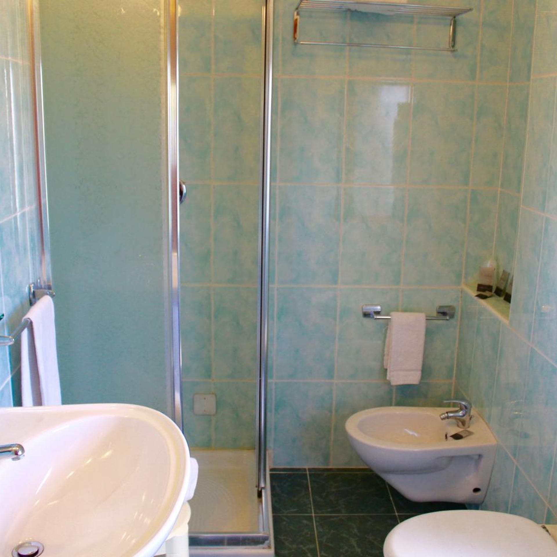 Un bagno con doccia vetro, lavandino e water.