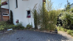 A residential building with a paved driveway, a small window with flowers, and a sign indicating parking. - Ferienwohnung Boger (Wannweil)