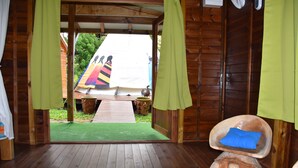 A wooden cabin with a wooden floor, a colorful rug, and a unique chair with a blue cushion. - CHALET "Danse du Tambour" 2 people - (Pointe-Noire)