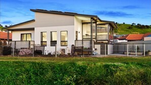 A modern two-story house with large windows and a flat roof. - Fairway 1 - 9/19 Troon Drive (NORMANVILLE)