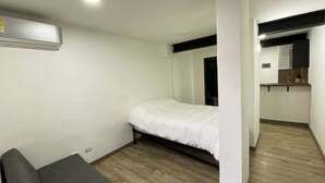 Une chambre comprenant un lit, un petit coin salon et une kitchenette.