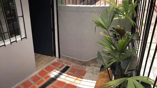 Un étroit couloir extérieur doté d’un sol en briques et d’une grille métallique.