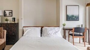 Une chambre à coucher avec un grand lit, un bureau, une chaise et une commode.
