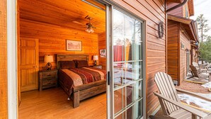 Een houten chalet met een slaapkamer, voorzien van een bed, twee nachtkastjes met lampen en een plafondventilator.