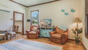 A living room with two leather armchairs, a striped rug, a television, and a lamp. - San Miguel Suite at Blanco Rapids Ranch (Wimberley)