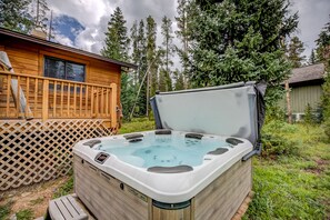 A hot tub in a backyard with a wooden deck and a wooden cabin in the background. - Royal Aspen Retreat Home: Lovely Setting, Spacious (Breckenridge)