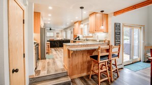 A kitchen with wooden cabinets, a granite countertop, and a bar area with stools. - Royal Aspen Retreat Home: Lovely Setting, Spacious (Breckenridge)
