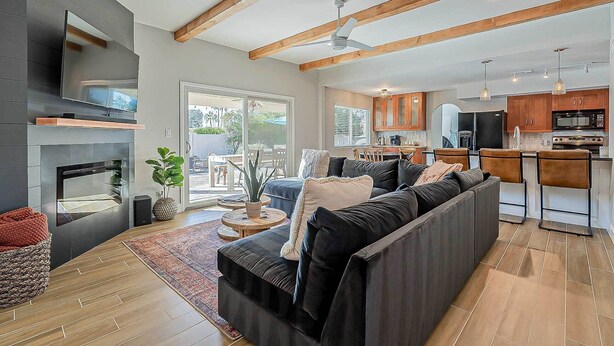 Una sala de estar moderna con chimenea, un sofá grande y una zona de comedor con una cocina al fondo.