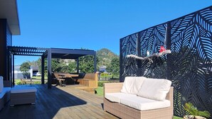 Eine Holzterrasse mit einem weißen Sofa und einer Pergola.