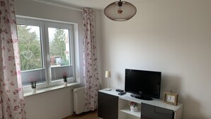 Ein modernes Wohnzimmer mit Flachbildfernseher, einem kleinen Tisch und einer dekorativen Lampe.