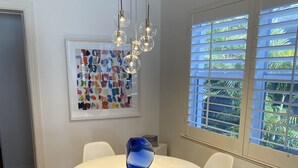 A dining area with a round table, white chairs, a blue vase, and a chandelier.