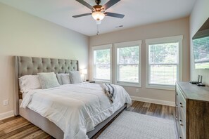 A bedroom with a tufted headboard, a bed with white bedding, a ceiling fan, and three windows with blinds. - Scenic Mtn Retreat w/ Wooded Backyard + Fire Pit! (Chattanooga)