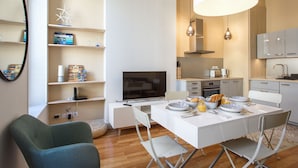 Una cocina moderna con comedor, muebles blancos amplios y una lámpara colgante grande.