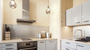 Una cocina moderna con electrodomésticos de acero inoxidable, armarios de madera e iluminación colgante.