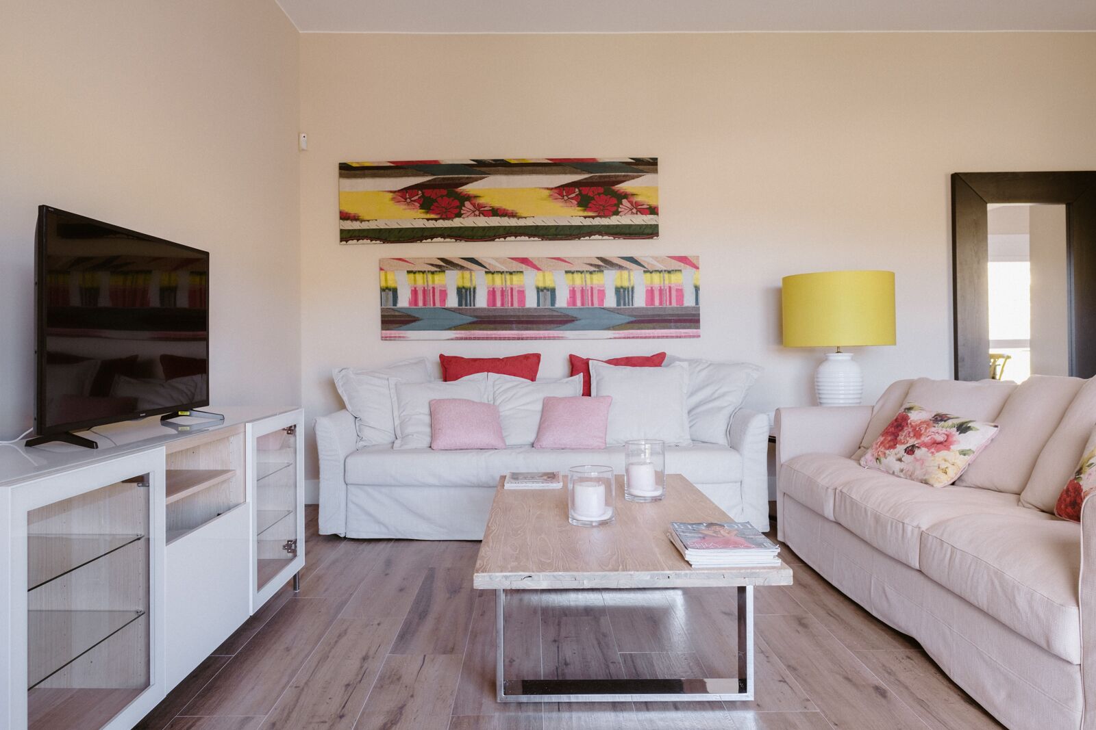 A modern living room with a white sofa, a coffee table, and a TV on a stand.