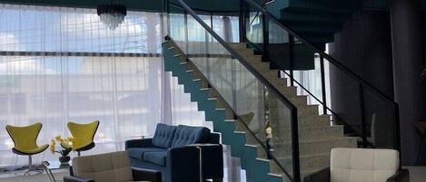 A spacious living area with a modern staircase, a round rug, and contemporary furniture.