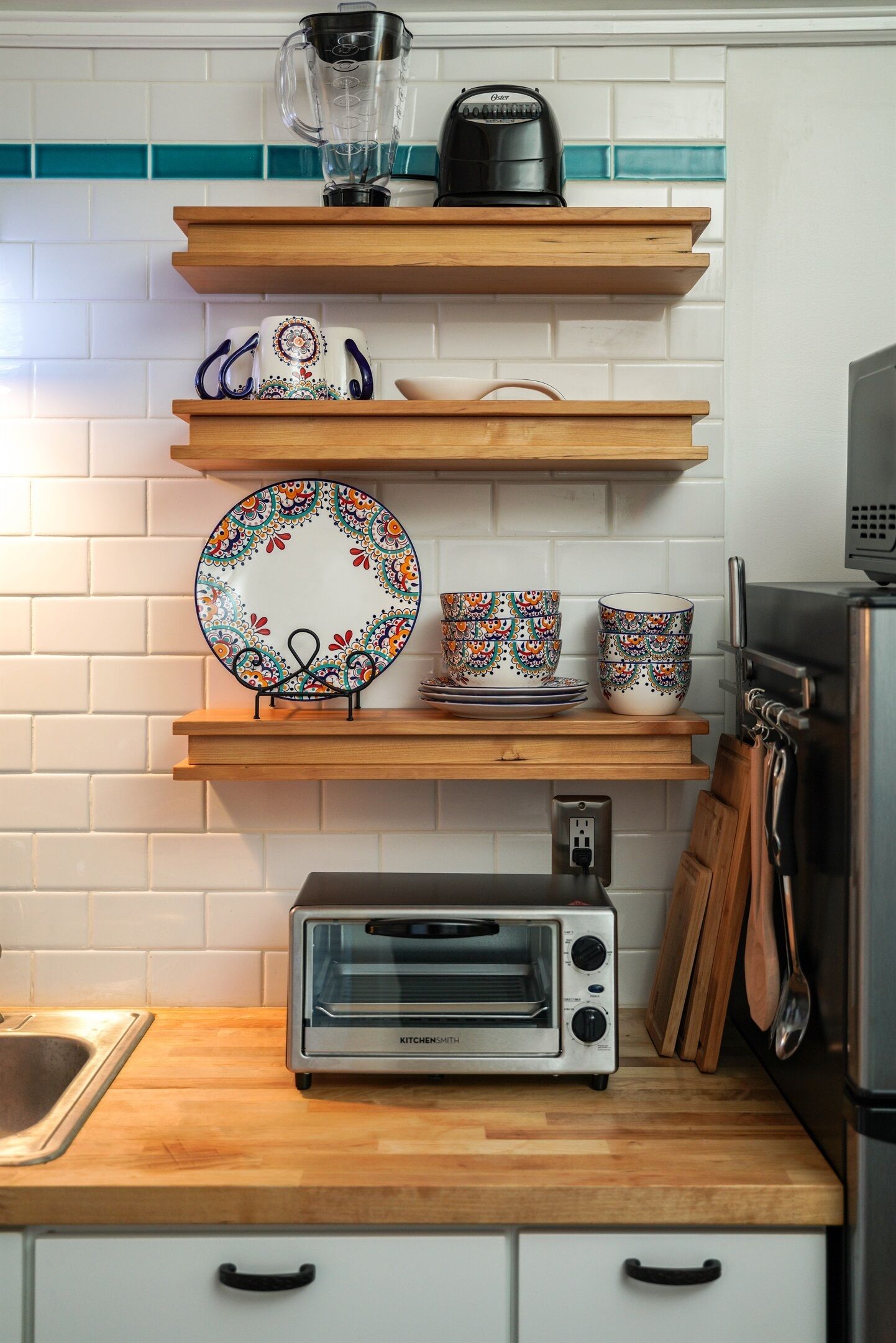 A kitchen with wooden shelves holding plates, cups, and a toaster.