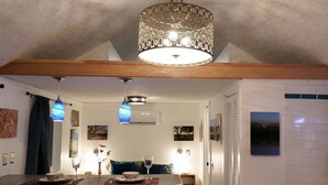 A modern kitchen with a central island, bar stools, pendant lighting, and a staircase leading to another level.