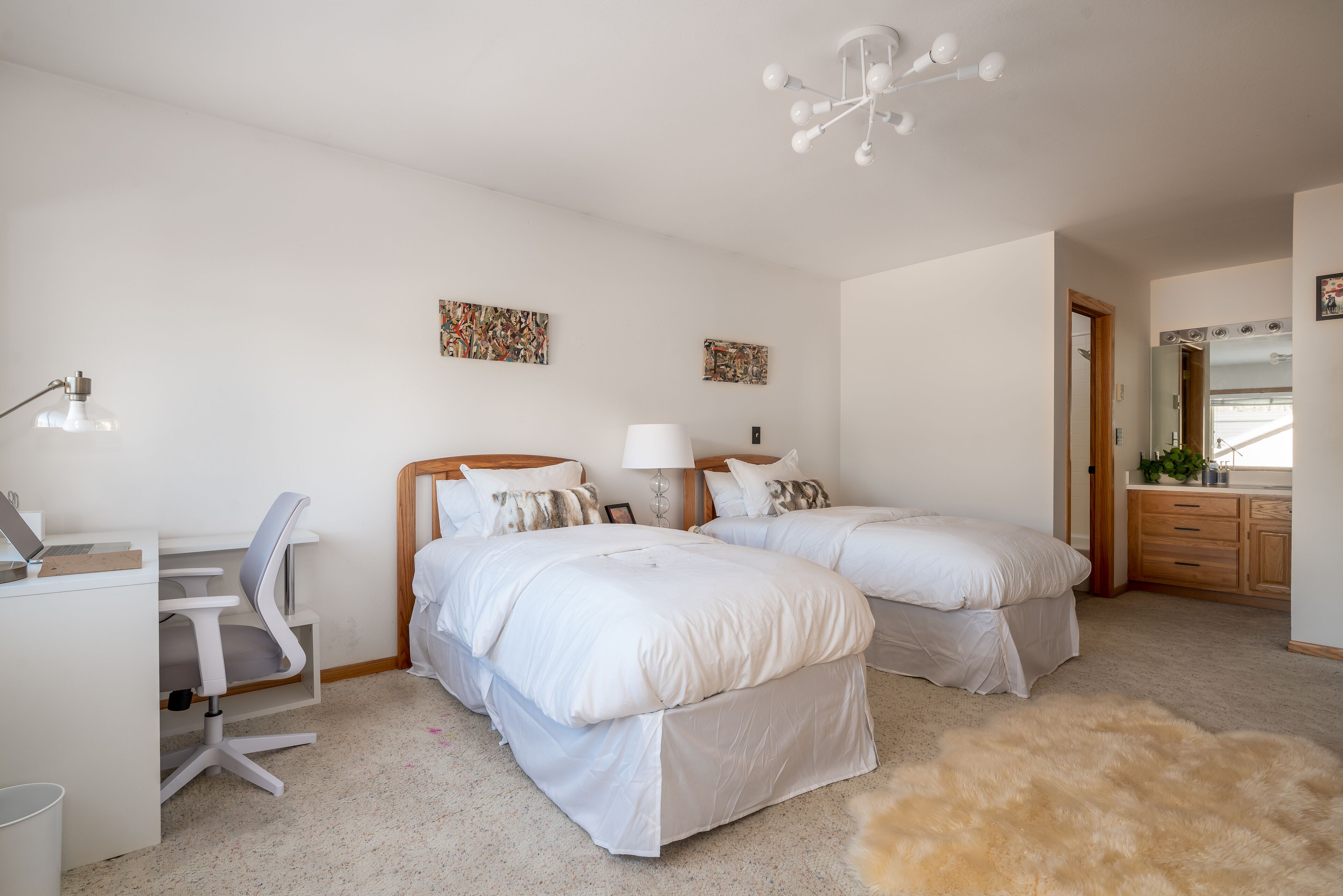 A bedroom with two beds, a desk, and a chair.