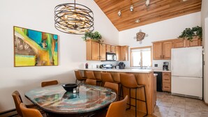 Een moderne keuken met houten kastjes, een centraal eiland en een eethoek met een ronde tafel en stoelen.