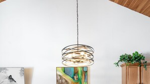 Een eethoek met een ronde tafel, bruine leren stoelen, een hanglamp en houten kasten.