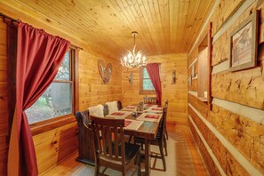Ein Holzhütten-Interieur mit Esstisch, Stühlen und einer Kandelaber.