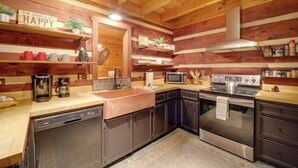 Una cucina in stile baita, con lavastoviglie, fornello, microonde e vari utensili da cucina.