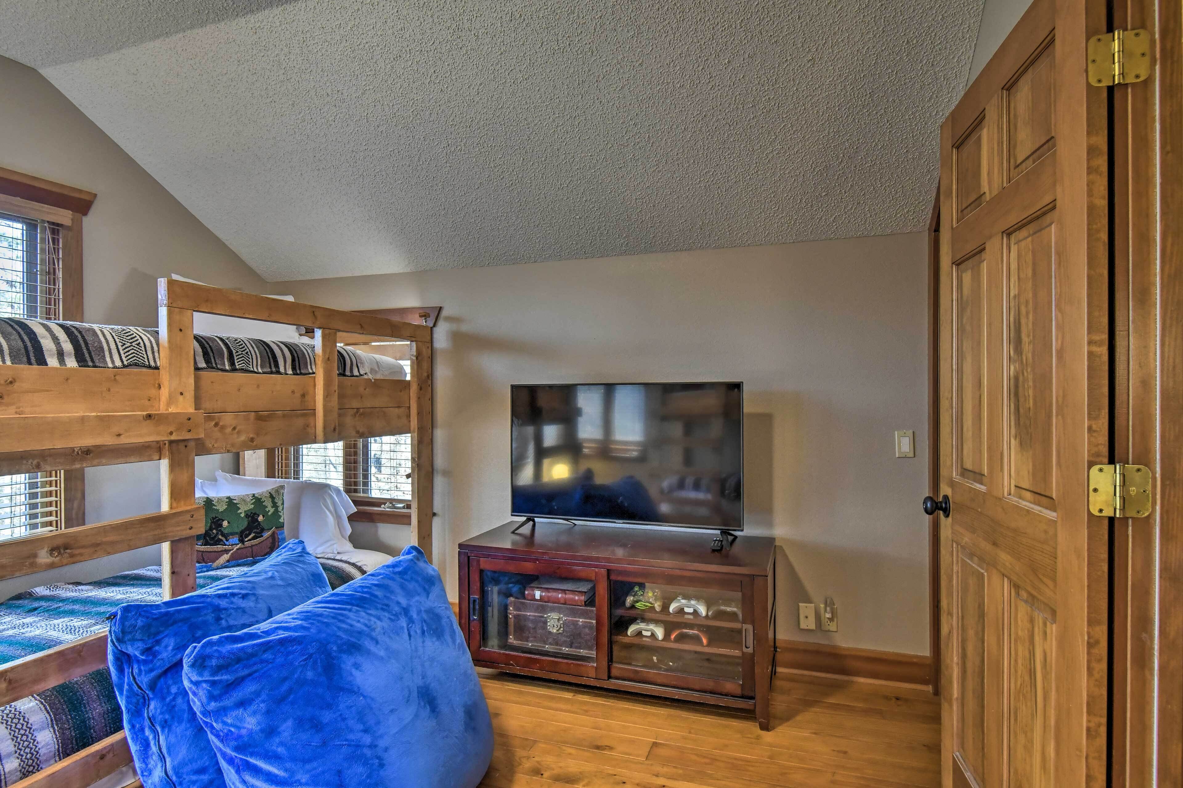 Ein Zimmer mit Etagenbetten, einem Fernseher auf einer Holzkommode und einer großen Holztür.