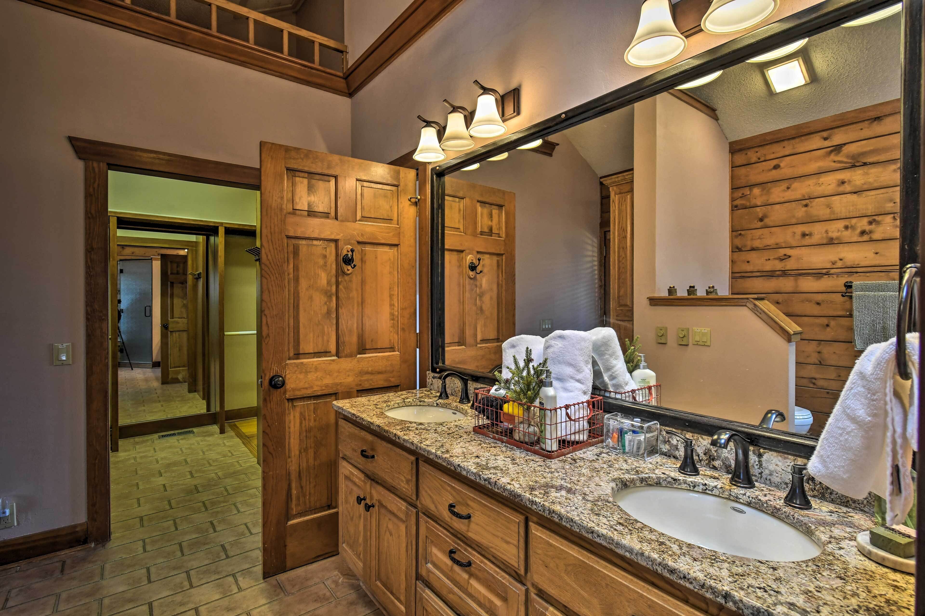 A bathroom with wooden cabinetry, a granite countertop, a large mirror, and a sink.