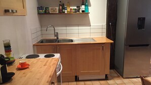 A kitchen with wooden cabinets, a stainless steel sink, a built-in oven, and a refrigerator.