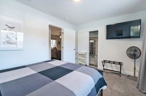 Un dormitorio con una cama grande, un televisor instalado en la pared y un armario con estantes.