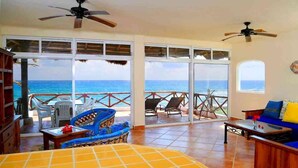 A room with a bed, a sofa, a table, and a view of the ocean. - Mi Casa Del Mar A6 - Captivating Sea Views from Terrace, Eco-Friendly - No A/C (Akumal)