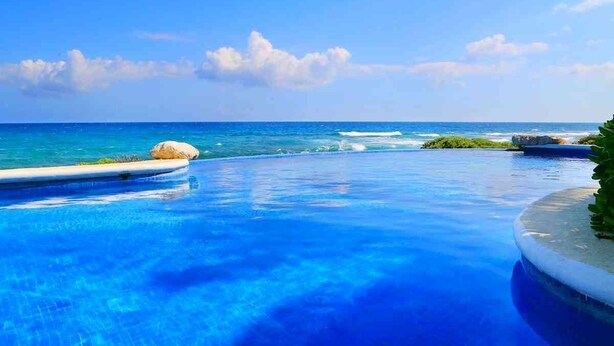 A clear blue pool with a view of the ocean and a rocky outcrop. - Mi Casa Del Mar A6 - Captivating Sea Views from Terrace, Eco-Friendly - No A/C (Akumal)