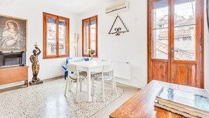 A room with a dining table, chairs, a statue, a painting, and a large window. - GuestHost - Bright apartment, of about 80 sqm with period furniture, which can accommodate up to 4 people, located on the third floor (NO lift) of a typical Venetian building. The building boasts a very central position: it is a two-minute walk from Piaz (Venezia)