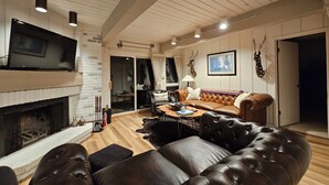 A cozy living room with a fireplace, leather sofa, and a television. - Interlude Ski-In Ski-Out~ Massage Chair, Hot Tub, <5 min walk to Snowmass Mall (Snowmass Village)