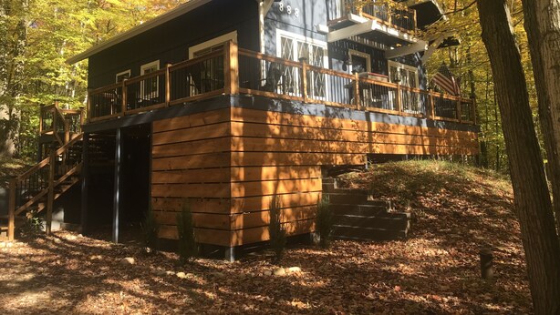 Une cabane dotée d’une terrasse en bois, d’un escalier et d’un balcon.