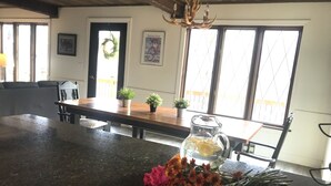 Une cuisine avec un plan de travail foncé, une table en bois et un vase de fleurs.