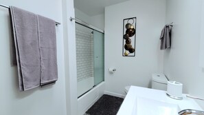 Een bad/douchecombinatie, een haardroger, handdoeken, zeep