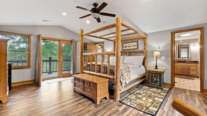 A spacious bedroom with a four-poster bed, wooden flooring, a ceiling fan, and a view through the glass doors. - Refuge Ranch Lodge | Log Cabin | Lake | Privacy | Weddings (Locust Grove)