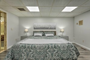 A bedroom with a large bed, two bedside tables, a headboard, a wall-mounted artwork, and a skylight.