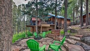 Eine Holzblockhütte mit einer Terrasse, Sitzgelegenheiten im Freien und einer Feuerstelle.