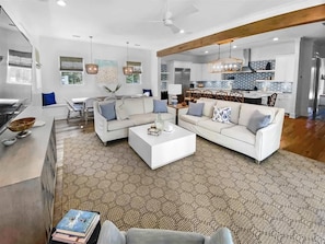 A modern living room with a white sofa, coffee table, and dining area.