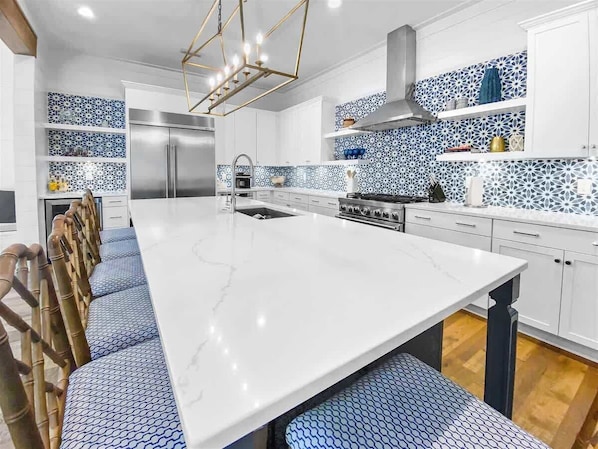 A modern kitchen with a large island, stainless steel appliances, and patterned backsplash tiles.