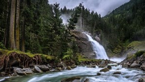 A waterfall cascading over rocks in a forested area. - Chalet in Krimml near Waterfalls (Krimml)