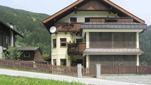 A two-story building with a balcony, a satellite dish, and a stone wall in front. - Chalet in Krimml near Waterfalls (Krimml)