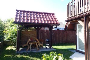 Une pergola en bois avec un toit en tuiles, située dans un jardin.