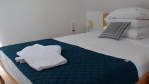 A neatly made bed with a teal quilt, white linens, and a folded white towel on the left side. - holiday home, Kolczewo (Kolczewo)