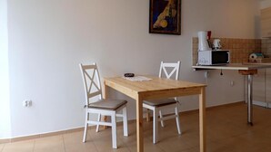 A small kitchen with a dining table and chairs, a microwave, and a painting on the wall. - holiday home, Kolczewo (Kolczewo)